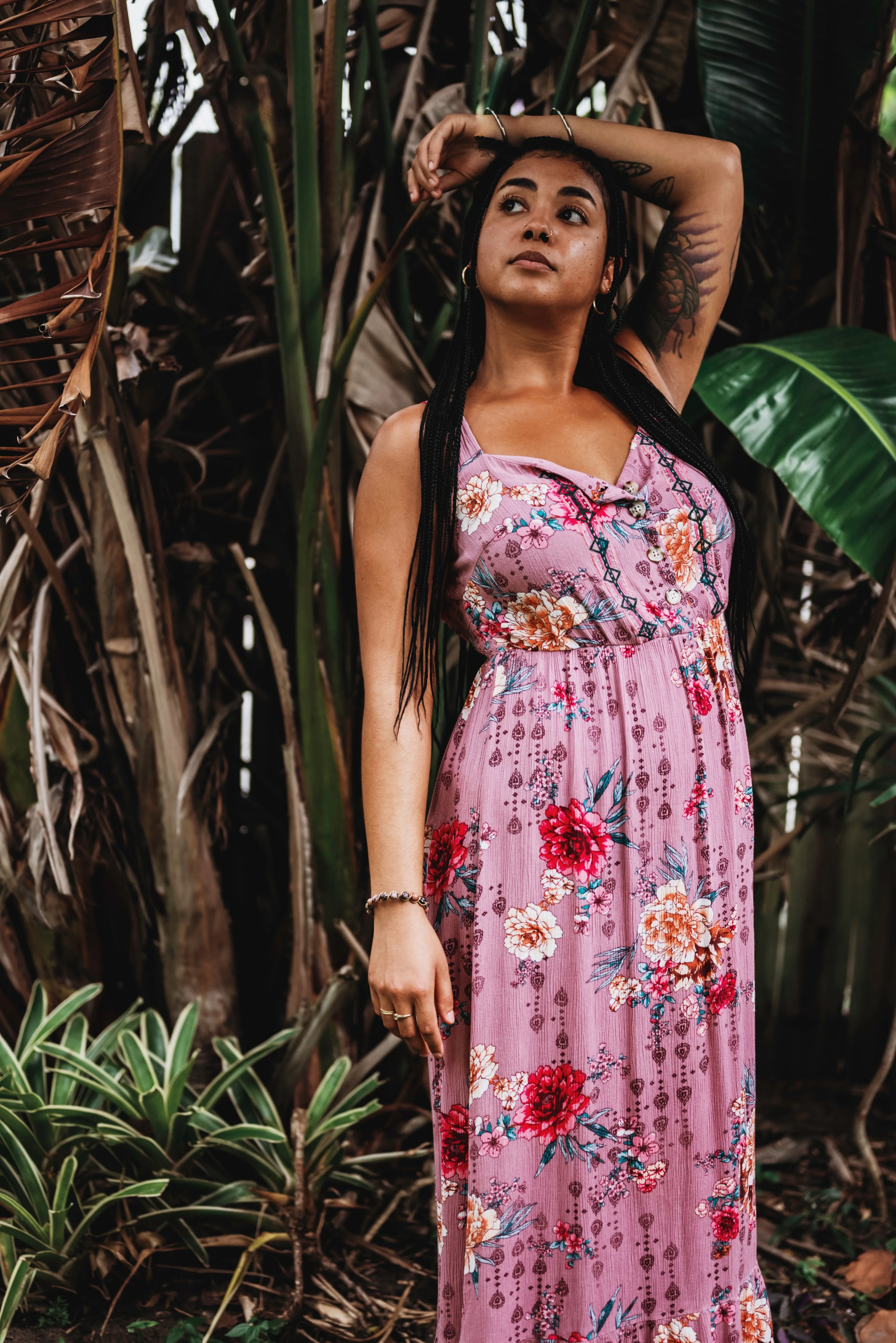 Areshika in a floral dress standing among tropical plants