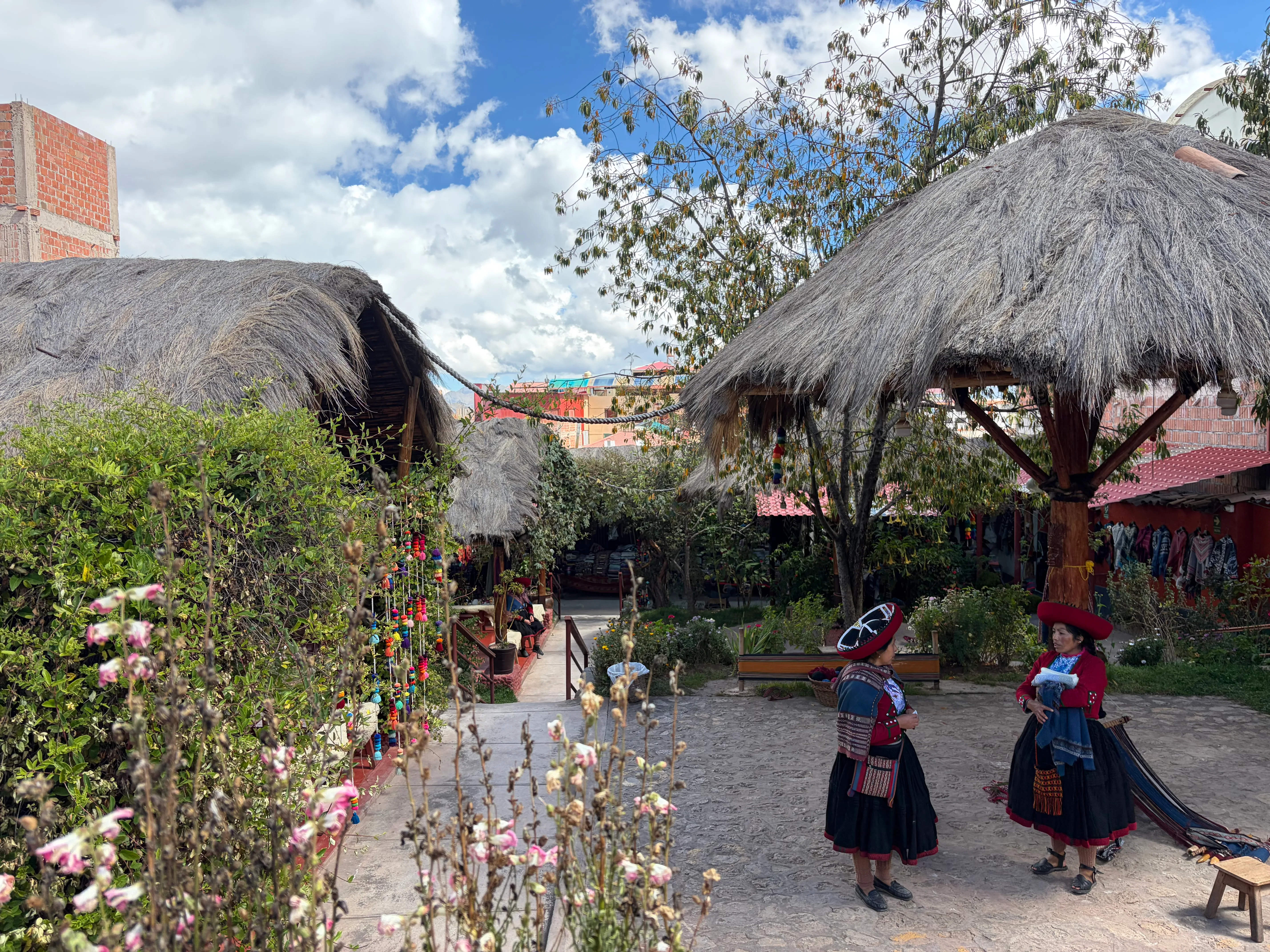 Courtyard garden with thatched shelters and women in traditional Andean dress
