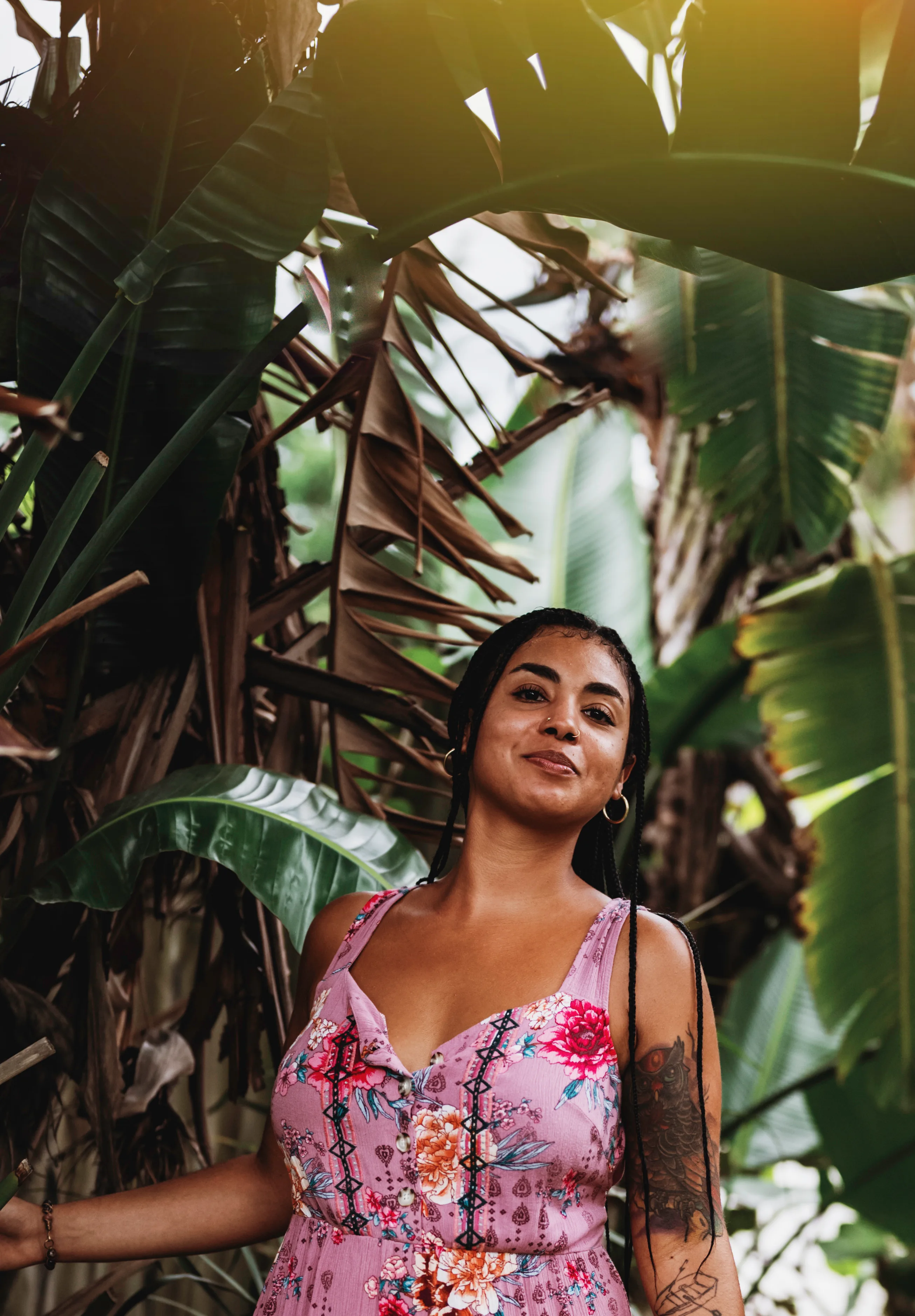 Areshika smiling beneath large tropical leaves