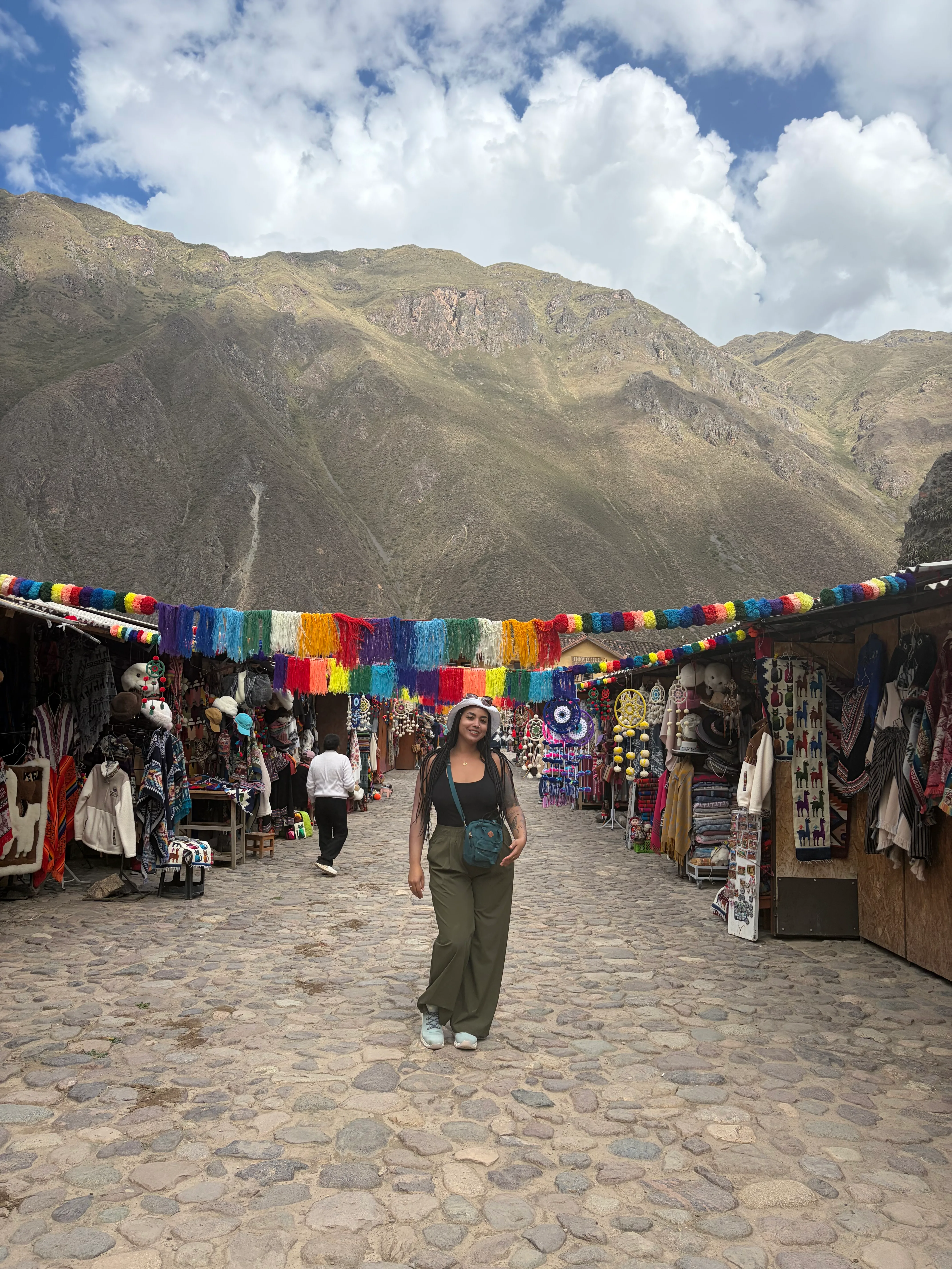 Market stall with colorful handwoven textiles and artisans under a reed roof in Peru
